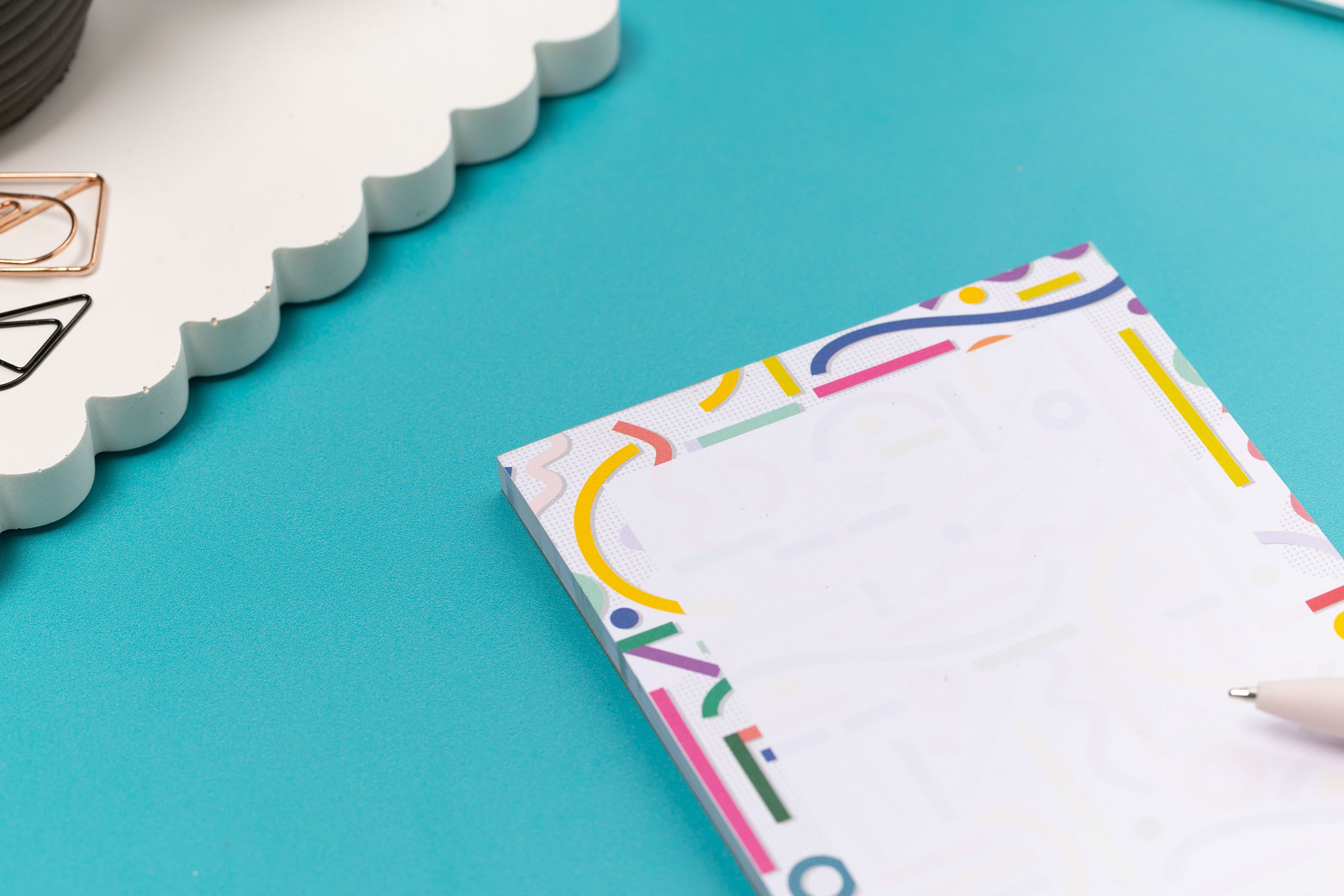 More detailed view of the Cutouts List pad is on a teal desk, with a white pen to its right.