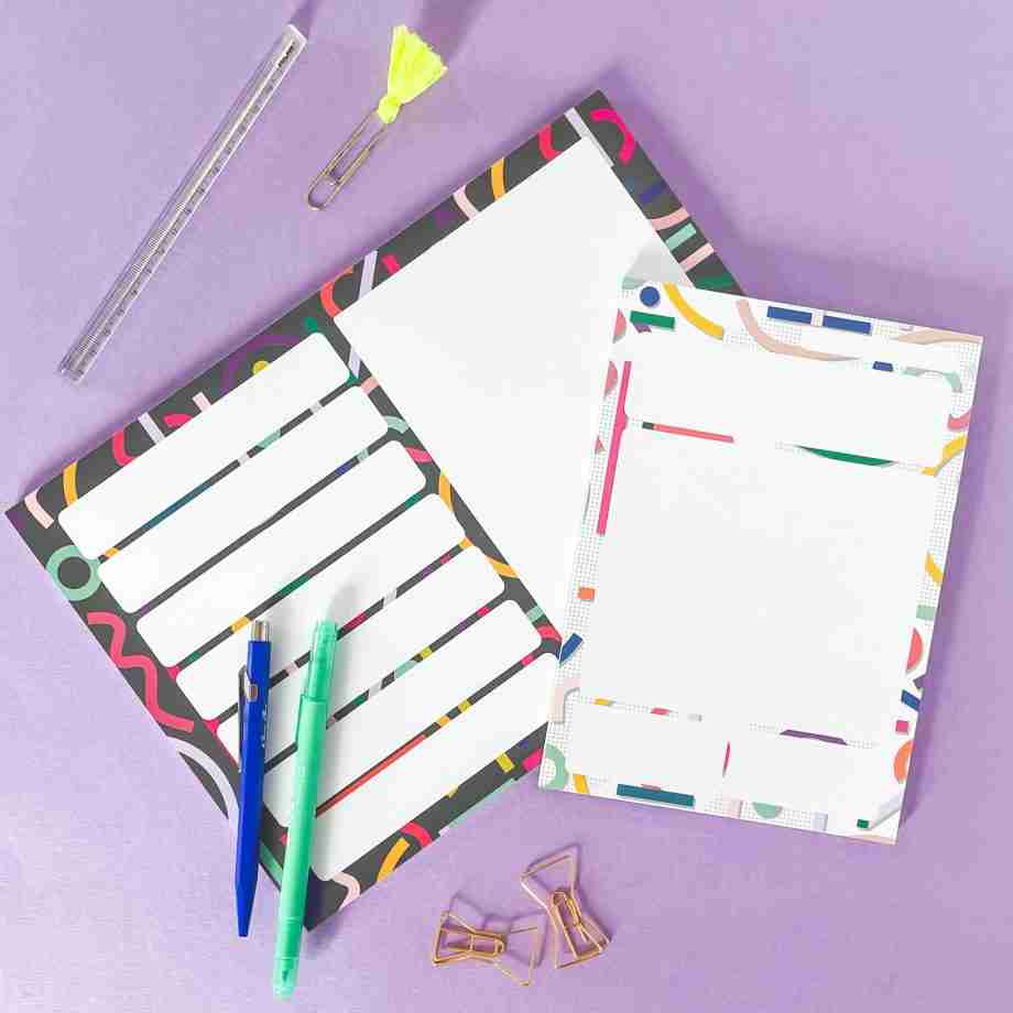 Cutouts Planner Gift Set - An A4 weekly planner pad is at the bottom with an A5 Daily planner pad resting on top. They are on a lilac desk with various pens and paperclips around them.