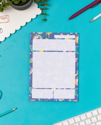 Paradise A5 Daily Planner Pad is central on a teal desk, with pens and a small plant around it.