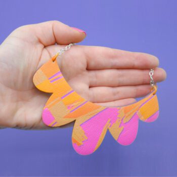 Handmade faux leather necklace and wood with a scalloped edge and a hot pink, orange, and purple abstract design.