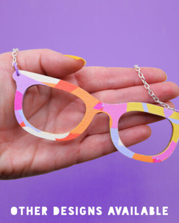 Vibrant, pop art glasses necklace in a bold pink, orange, purple and yellow geometric design.