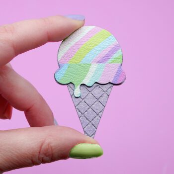 A pastel coloured ice cream brooch held in fingertips with pastel painted nails. A playful handmade accessory with a fun geometric design