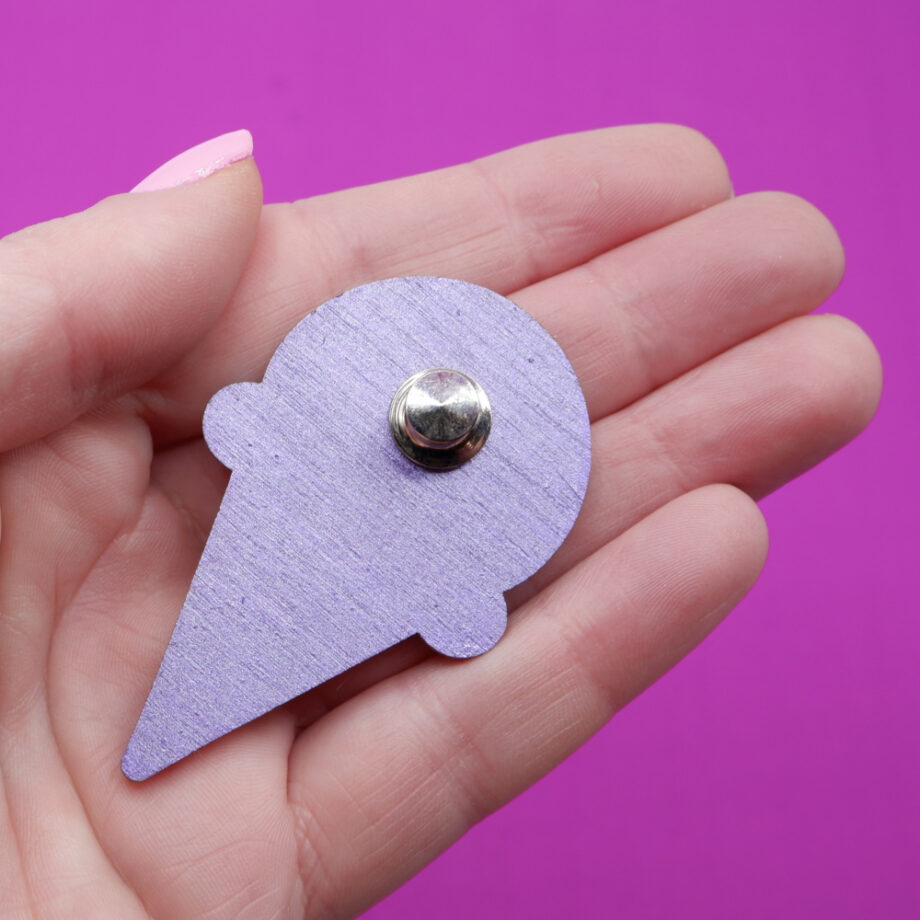 Shows the metallic purple painted reverse of a handmade wooden and fabric brooch in the shape of a cute ice cream cone.