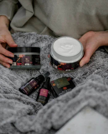 Pink Prestige whipped shea butter displayed with other skincare products on soft grey velvet fabric, styled as a luxurious self-care gift set.