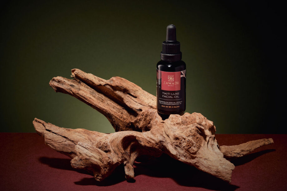 Tikiti Luxe facial oil bottle balanced on a wooden stick, highlighting its elegant design and natural aesthetic.