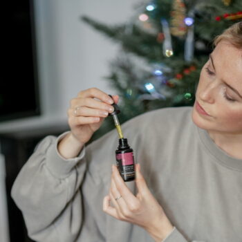 Woman holding a bottle of Tikiti Luxe facial oil and dropper, looking at it with admiration.