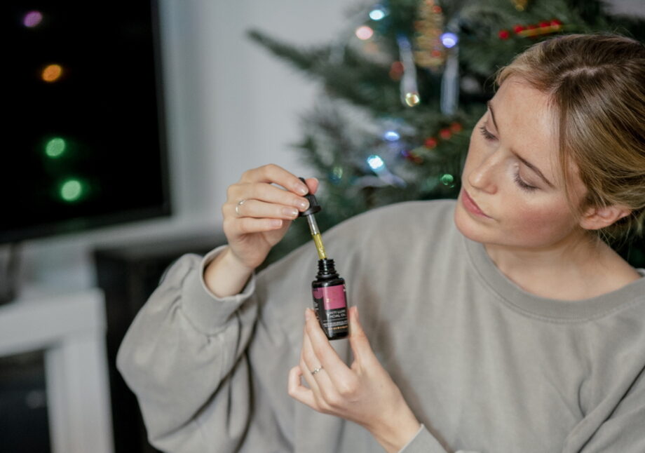 Woman holding a bottle of Tikiti Luxe facial oil and dropper, looking at it with admiration.