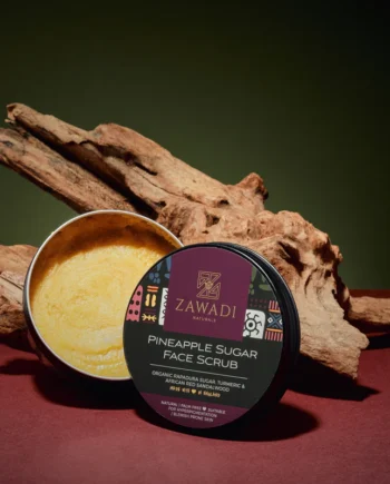 Open jar of Pineapple, Camwood & Turmeric Sugar Scrub on a wooden stick, showing rich texture and golden hue