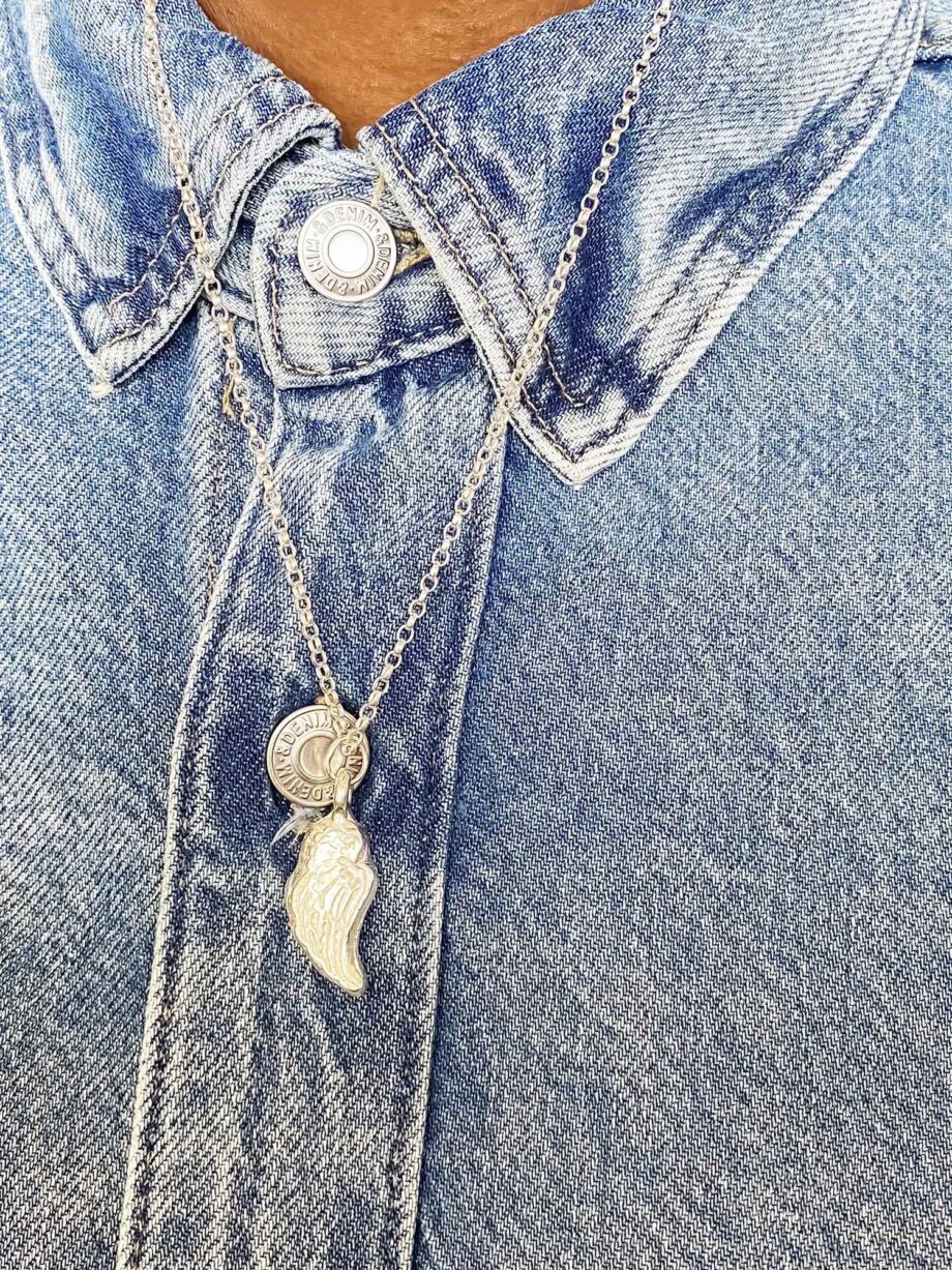 Angel wing pendant necklace worn over a denim shirt