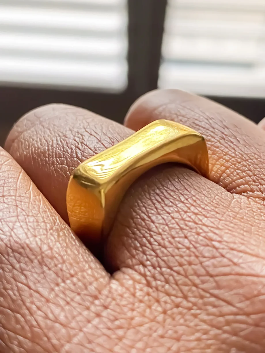 Close-up of gold Asymmetric Grace Bow Ring worn on finger, showing smooth texture and shape
