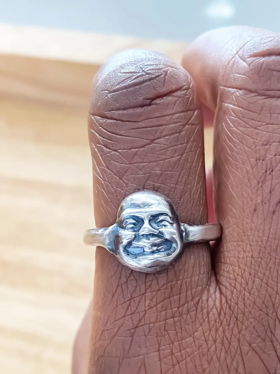 Close-up of single Buddha Face Ring on finger, natural lighting