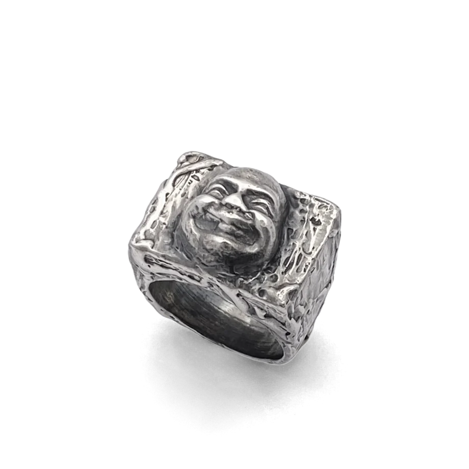 Angled side view of the Buddha Face Ring in oxidised silver on white background