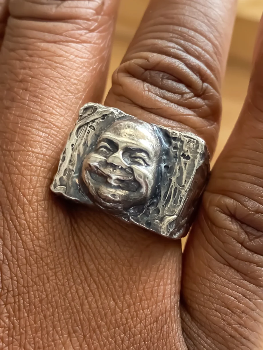 Close-up of Buddha Face Ring on finger showing detailed facial features