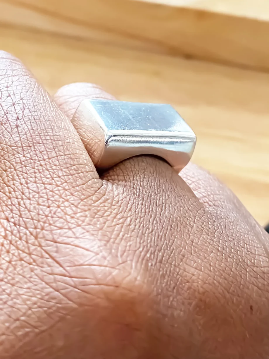 Silver square signet ring worn on hand, top-down view
