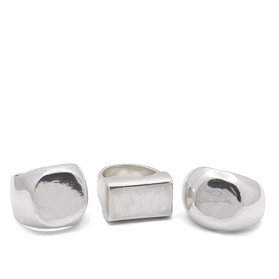 Three handcrafted silver signet rings with different face shapes displayed on a white background