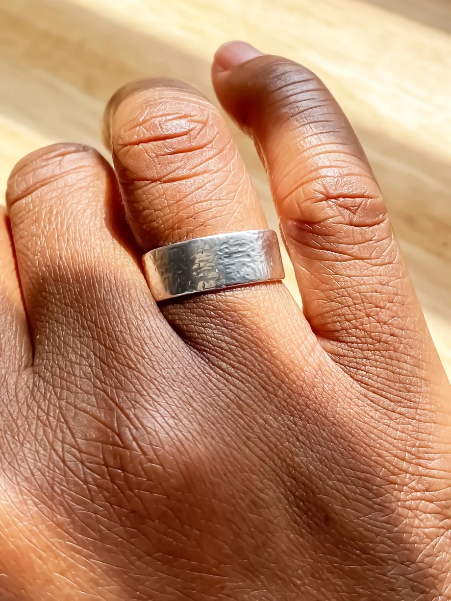 lose-up of hammered silver ring on a hand in natural lighting.