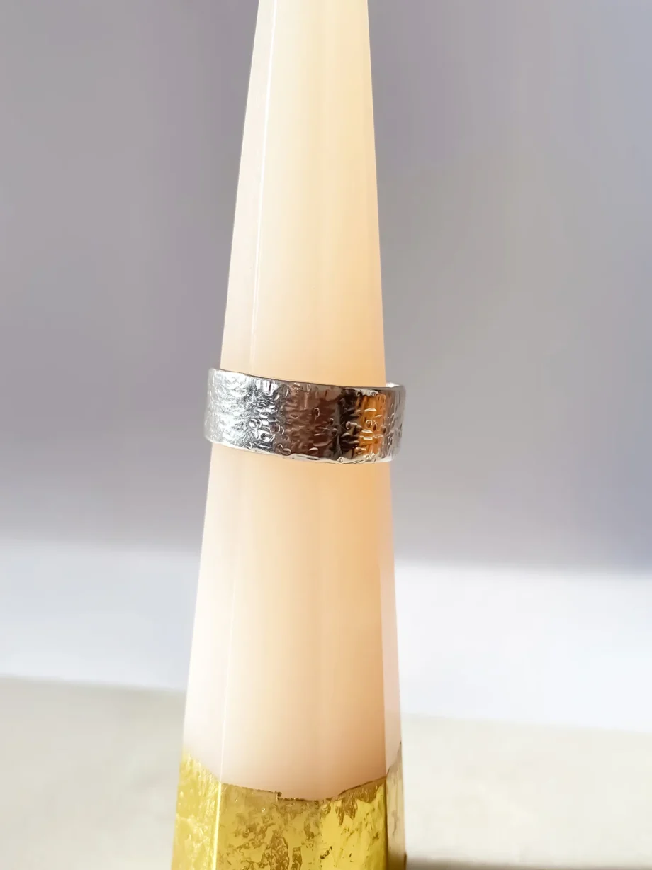Silver hammered ring displayed upright on a ring cone.