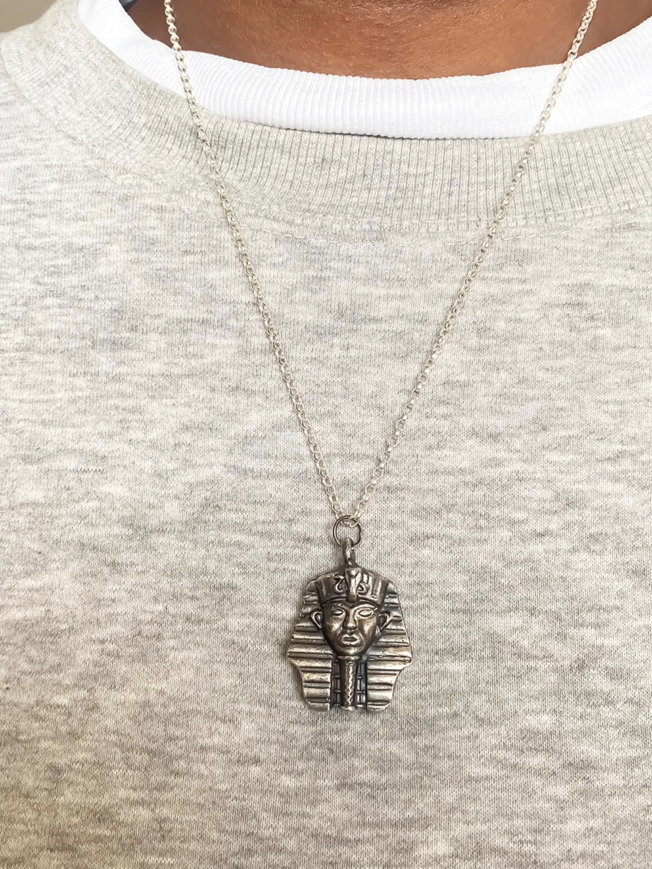 Pharaoh Pendant worn on a chain over a grey top.