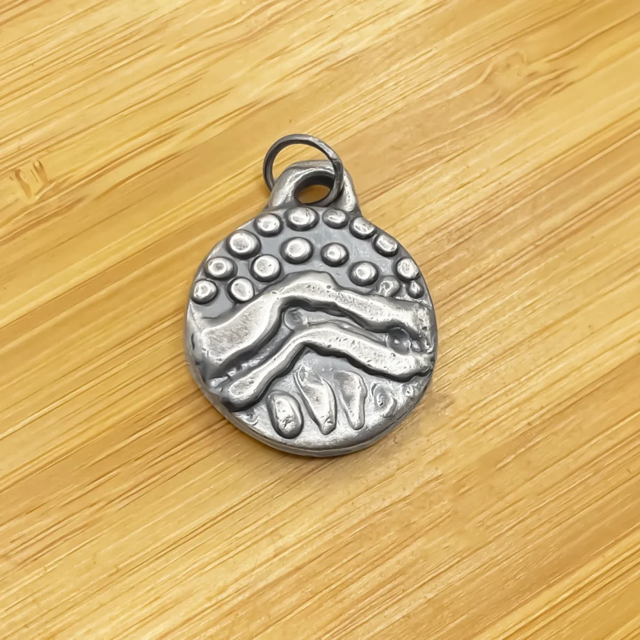 Close-up of Wavy Detail Pendant without chain on wooden background
