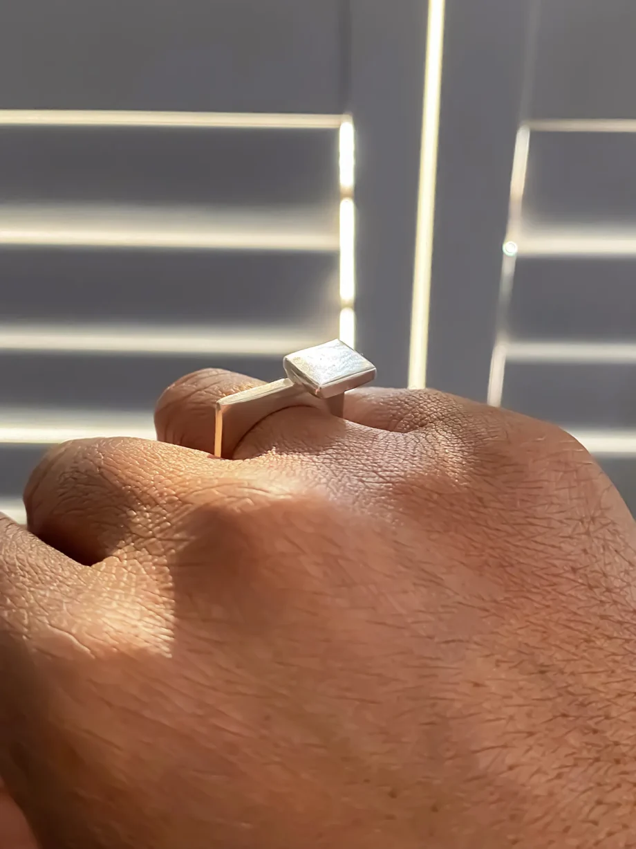 Angled view of square-top silver signet ring on hand