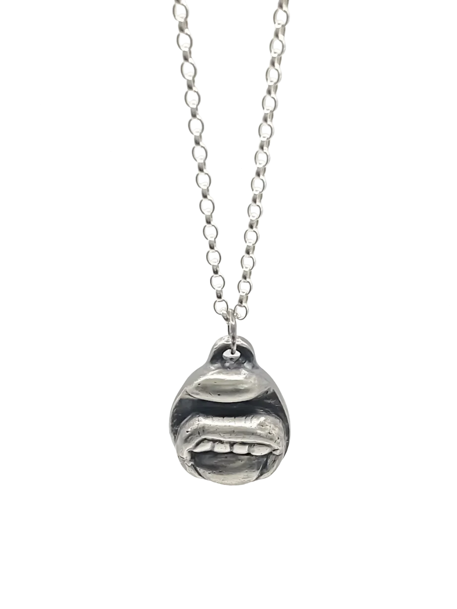 Close-up of the Tongue & Teeth Pendant in sterling silver on a chain, set against a white background