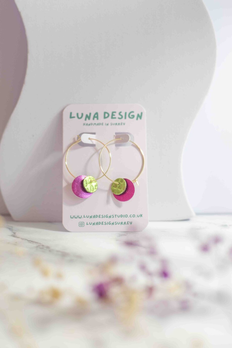 Pink and green circle-shaped leather on 30mm gold plated hoops, displayed on a neutral background