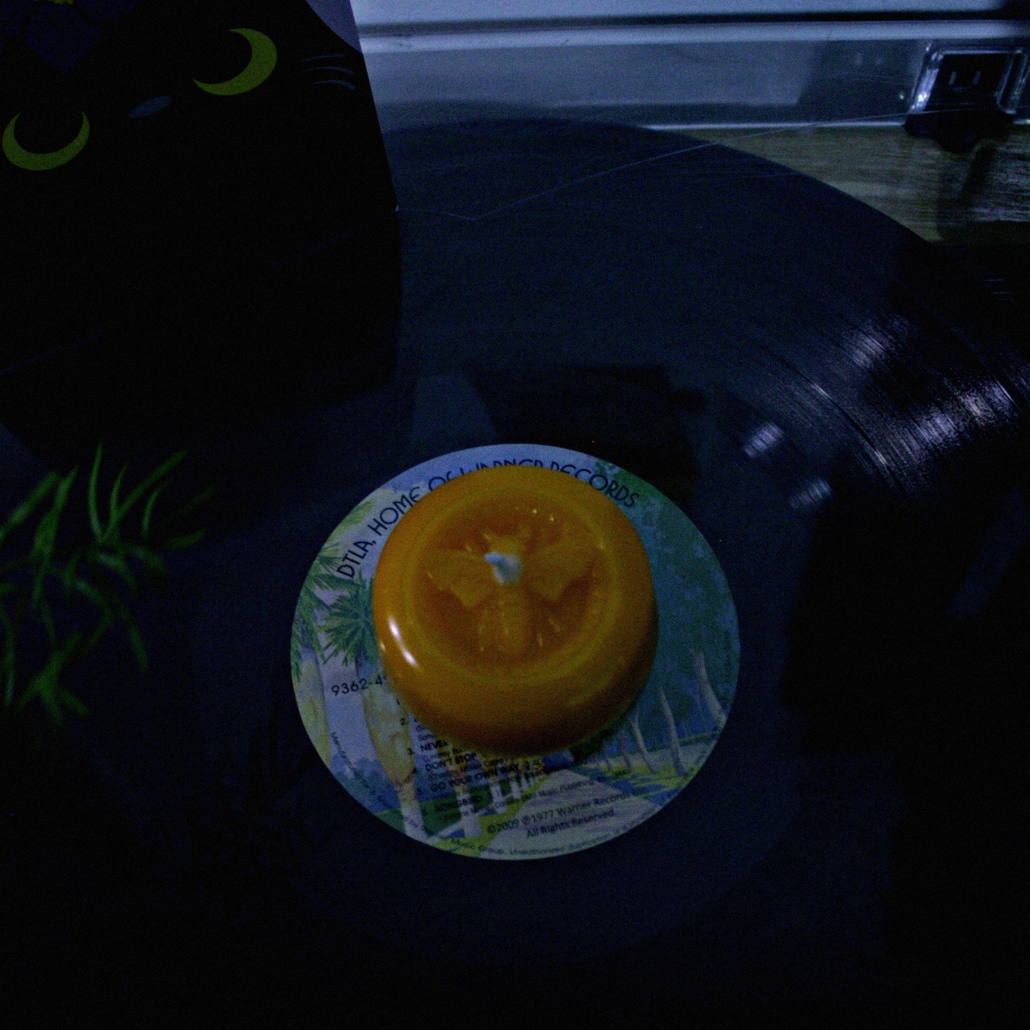 Round yellow candle with a bee imprint on a record-player