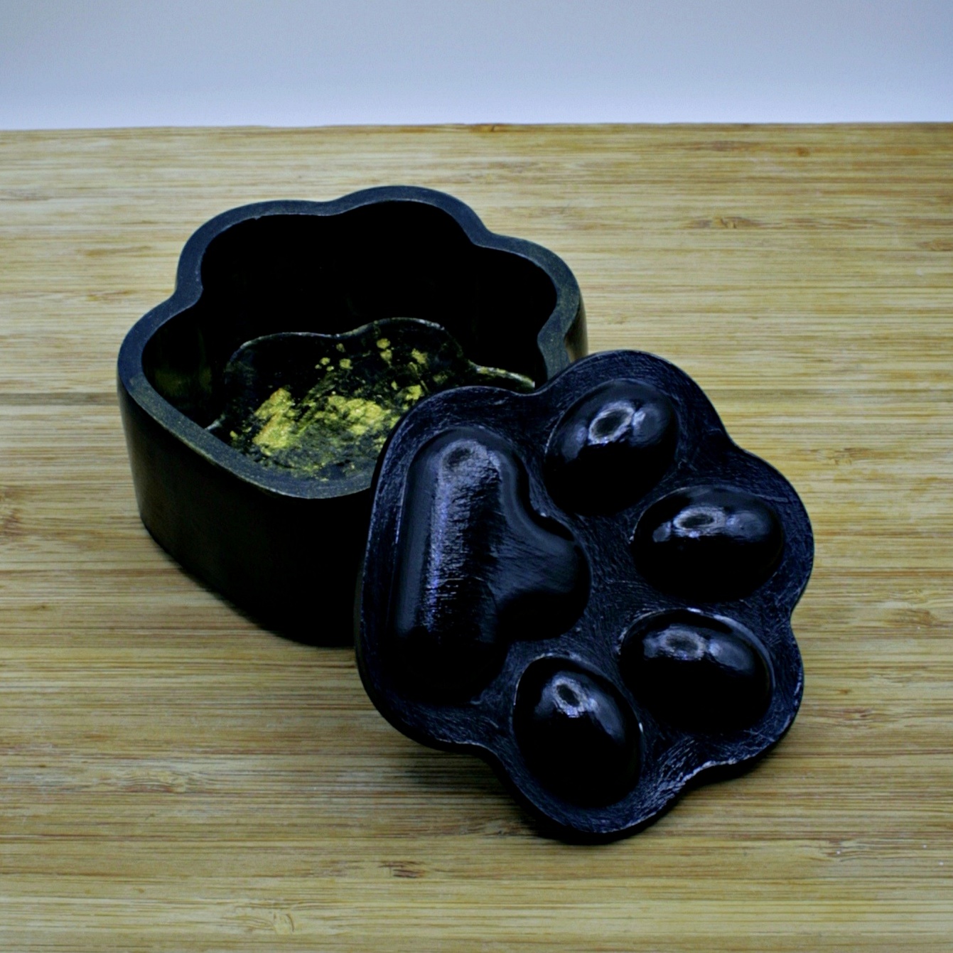Black paw-shaped box with golden glitters inside