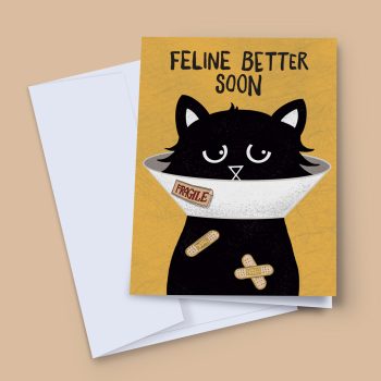 Feline Better Soon get well card showing a grumpy black cat wearing a cone of shame with a fragile sticker and two plasters on its chest, bold hand-lettered text on a mustard yellow background, shown with white envelope