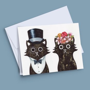 Illustrated greeting card showing two black cats, one wearing a top hat and bow tie and one wearing a floral crown, printed on white card stock with a white envelope, by Baldy and the Fidget