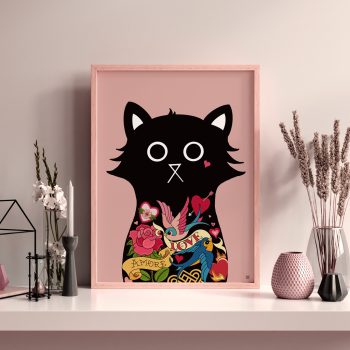 A4 wall art print of a black cat with tattoo flash designs including roses, swallows and love banners, in a pink frame, styled on a shelf with dried flowers and decorative vases.